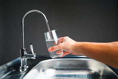 hand pouring a glass of water from filter tap